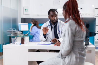 Patient with pregnancy discussing with general practitioner about healthcare and parenthood at consultation