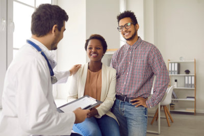 Male doctor comfort support multiracial couple patients at consultation in clinic